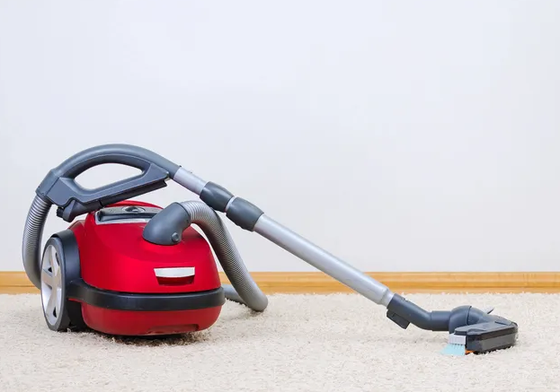 A red vacuum cleaner is on the floor